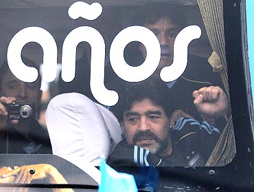 Argentina's national coach Diego Maradona waves to fans from the Argentina team bus, in Buenos Aires, before leaving for South Africa