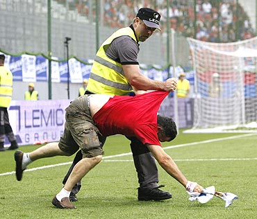 A Serbian supporter is grabbed by a security guard after entering the pitch during the international friendly between Serbia and New Zealand in Klagenfurt