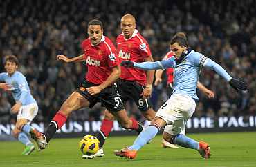 Man City's Carlos Tevez fights for the ball with Man United's Rio Ferdinand