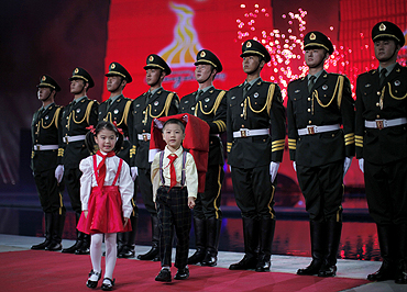 Two children walk away after handing China's national flag to the soldiers during the opening ceremony