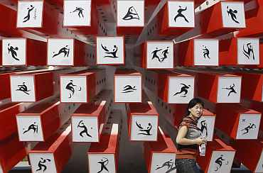 A woman walks past an installation depicting sporting events at the Athletic stadium for the Asian Games in Guangzhou