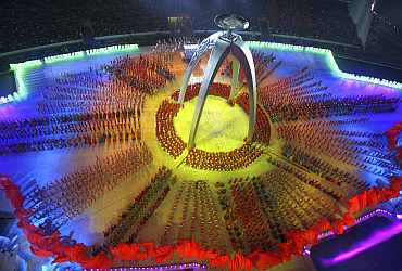 Participants perform near the torch for the Asian Games during a rehearsal for its opening ceremony