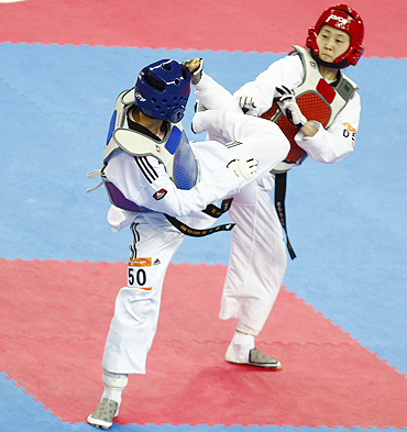China's Hou Yuzhuo (blue) fights South Korea's Lee Sung-hye during their women's taekwondo under 57k