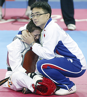 Taiwan's Yang Shu-Chun is consoled by her coach while staging a sit-in protest after she was disqualified when leading Thi Hau Vu of Vietnam 9-0 in their taekwando 49kg bout on Wednesday