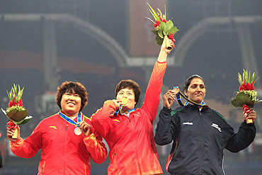 China's gold medalist Li Yanfeng (C) stands with compatriot silver medalist Song Aimin and India's bronze medalist Krishna Poonia after the women's discus throw final during the 16th Asian Games in Guangzhou