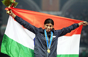 India's Ashwini Chidananda Akkunji celebrates with her gold medal after winning the women's 400m hurdles event at the 16th Asian Games in Guangzhou