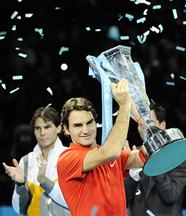 Roger Federer lifts the trophy as Rafael Nadal applauds after their World Tour Finals match on Sunday