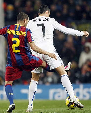 Real Madrid's Cristiano Ronaldo and Barcelona's Dani Alves vie for possession