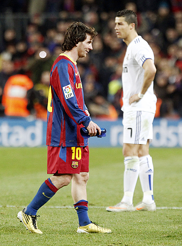 Barcelona's Lionel Messi (left) walks past Real Madrid's Cristiano Ronaldo