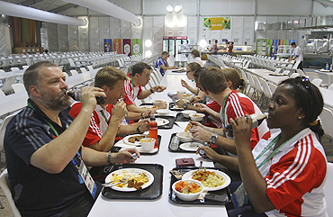 Members of the England Commonwealth Games team enjoy a meal at the food court in the Games Village