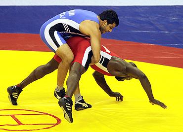 Manoj Kumar (blue) challenges Nigeria's Joe Agbonavbare during their 84 kg men's wrestling bout