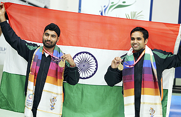 Indian gold medallists Gurpreet Singh (left) and Omkar Singh with the national flag after winning the men's pairs 10m air pistol shooting final on Thursday