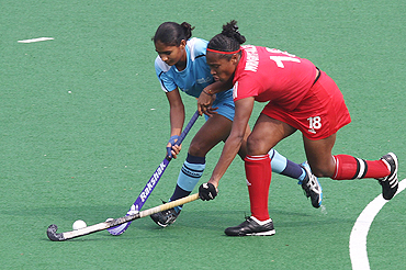 Trinidad and Tobago captain Patricia Wright-Alexis (right) and India's Poonam Rani fight for the ball during their women's hockey group match on Friday