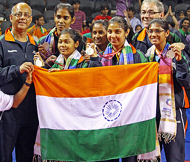 Indian table tennis stars Mouma Das, Shamini Kumaresan, Poulomi Ghatak, Mamta Prabhu and Madhurika Suhas with their coaches Marcos Constantini (right) and Bhawani Mukherjee (left) after winning the silver medal on Saturday
