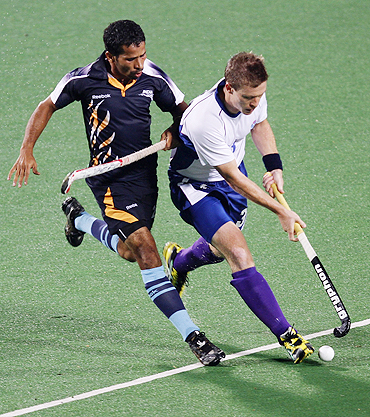Scotland's Derek Salmond (right) and India's Bharat Chiraka fight for possession during their men's hockey group match on Saturday