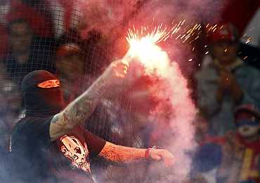A supporter of Serbia's soccer team holds a lit flare before the team's Euro 2012 qualifying match against Italy in Genoa