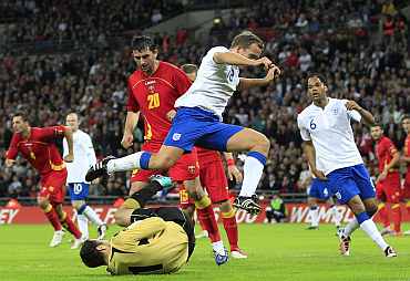 England's Kevin Davies jumps over Montenegro's goalkeeper Mladen Bozovic during their Euro 2012 qualifying match