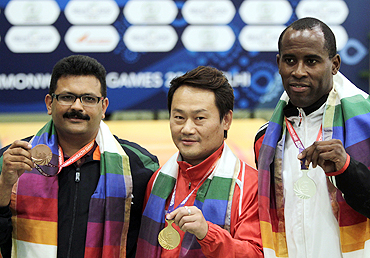 Singapore's gold medallist Gai Bin (centre) poses with Trinidad's silver medallist Peter Roger Daniel (right) and India's bronze medallist Samaresh Jung after winning the men's singles 25m standard pistol shooting finals on Wednesday
