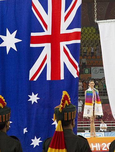 Australia's Naazmi Johnson watches her national flag is raised after winning gold during rhythmic gymnastics event on Wednesday