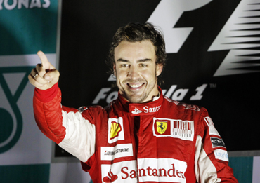Ferrari Formula One driver Fernando Alonso of Spain points as he celebrates on the podium after winning the South Korean F1 Grand Prix