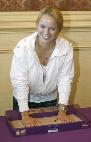 Caroline Wozniacki leaves her handprints after a news conference held for the WTA Tour Championships in Doha