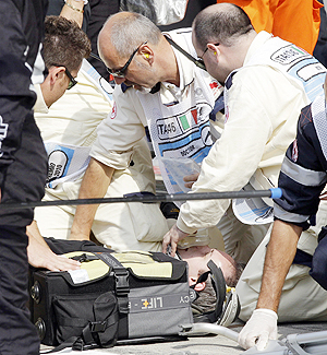 A Hispania Racing Team radio engineer receives first aid after being hit by a wheel of Hispania driver Sakon Yamamoto during the Italian F1 Grand Prix on Sunday