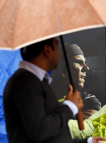 A fan walks past a poster of Rafael Nadal during a rain delay before the start of the men's final at the US Open