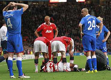 Manchester United players comfort injured team mate Valencia as Rangers' Broadfoot, Bougherra and Naismith look on