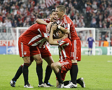 Bayern Munich's Thomas Mueller (kneeling) celebrates with teammates after scoring against AS Roma