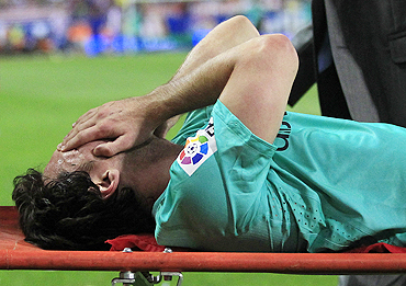 Lionel Messi grimaces as he is led out on a stretcher after getting injured
