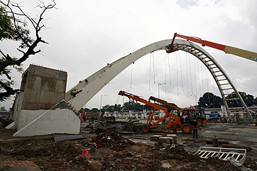 A crane removes waste from a collapsed pedestrian bridge outside the Jawaharlal Nehru Stadium in New Delhi