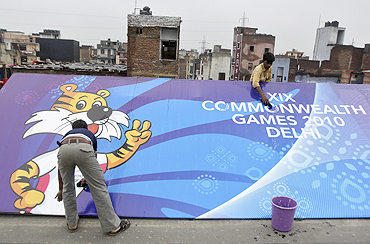 Workers clean a billboard outside the Commonwealth Games athletes village in New Delhi