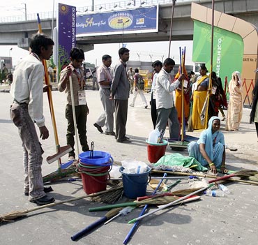 Workers prepare their brooms before entering the Games village