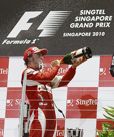 Ferrari Formula One driver Fernando Alonso of Spain sprays champagne as he celebrates on the podium after winning the Singapore GP
