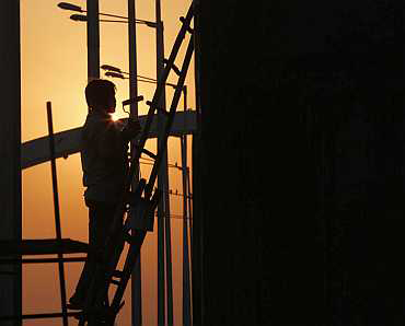 A labourer works on a flyover beside the Jawaharlal Nehru Stadium in New Delhi