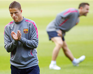 Barcelona's Ibrahim Afellay (left) gestures as teammate Xavi Hernandez (background) goes through the grind at a training session