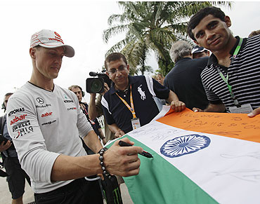 Mercedes's Michael Schumacher signs autographs on an Indian flag in the paddock