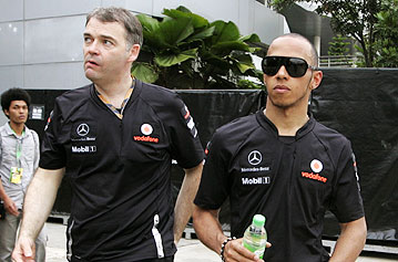 McLaren's Lewis Hamilton (right) leaves the paddock after the Malaysian Grand Prix