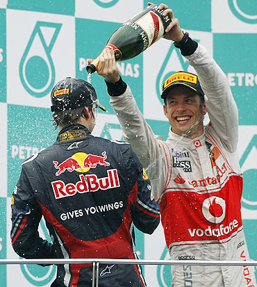 McLaren's Jenson Button (right) and Red Bull's Sebastian Vettel spray champagne on each other after winning the Malaysian GP on Sunday