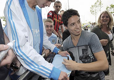 Samir Nasri signs autographs as he is greeted by fans outside Manchester City's Etihad Stadium in Manchester on Wednesday