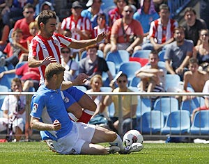 Atletico Madrid's Adrian Lopez and Osasuna's Sergio Fernandez (bottom) fight for possession during their La Liga match on Sunday