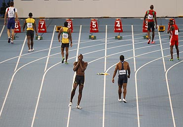 Usain Bolt (centre) of Jamaica reacts after being disqualified for a false start