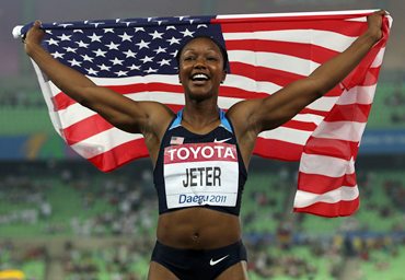 Carmelita Jeter of United States celebrates with her country's flag after the women's 100 metres final