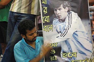 A Messi fan holds up a Messi poster outside the Kolkata airport