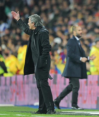 Head coach Jose Mourinho (left) of Real Madrid reacts beside coach Josep Guardiola of FC Barcelona