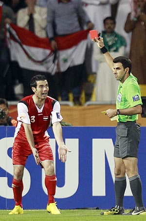 Syria's Nadim Sabag (left) gestures toward referee Mohsen Torky of Iran as he is issued a red card during their Asian Cup Group B match against Japan on Thursday
