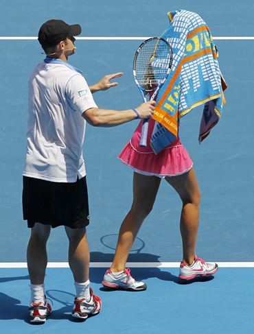 Victoria Azarenka covers her head with a towel as Andy Roddick watches