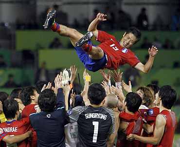 South Korea's players throw Lee Young-pyo in the air after winning their 2011 Asian Cup third place playoff match against Uzbekistan