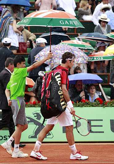 Roger Federer leaves the court as rain stops the play during his men's final match against Rafa Nadal at the French Open