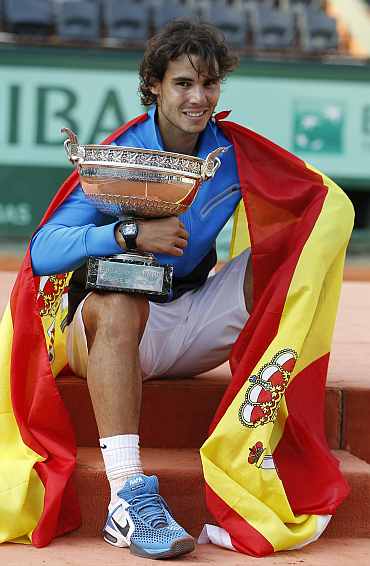 Rafa Nadal poses with the trophy and the Spanish flag during the ceremony after defeating Federer during their men's final at the French Open